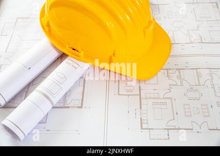 Construction project. Yellow safety helmet and building blueprint plans, copy space. Architect engineer office Stock Photo