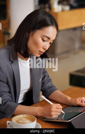 Busy Asian business woman using digital tablet writing e signature. Stock Photo