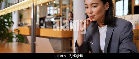 Young Asian business woman using laptop computer working during lunch in cafe. Stock Photo