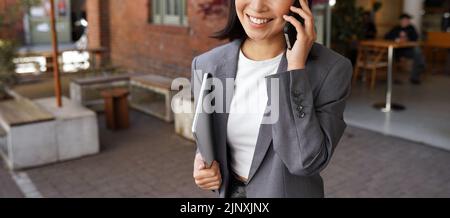 Young business woman manager wearing suit talking on phone making call outdoor. Stock Photo