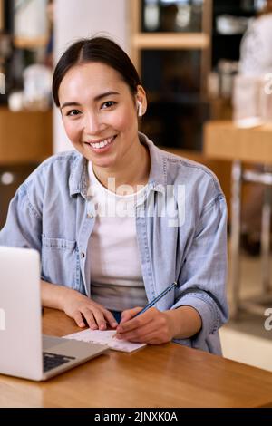 Young smiling Asian woman student elearning online using laptop. Stock Photo