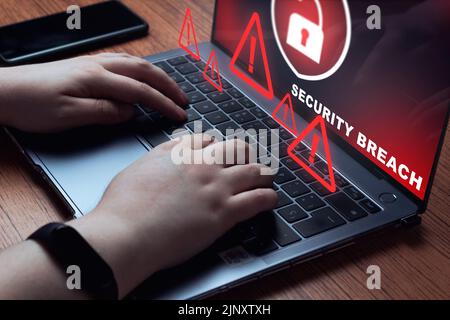 Woman using laptop with system breach warning on screen. Cyber security data protection business technology. Stock Photo