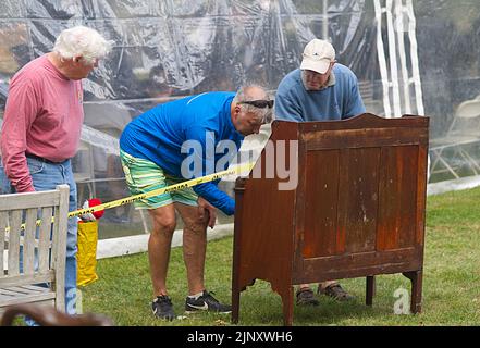 Examining an item for auction at a church flea market in Dennis, Massachusetts on Cape Cod Stock Photo