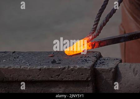 close up of hot-up metal rod on anvil in forge Stock Photo