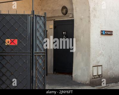 Public toilet door with wheelchair sign reserved for the disabled. Next to it an iron screen with the no-entry sign due to work in progress Stock Photo