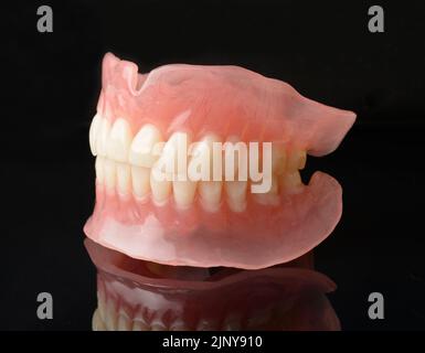 Modern full denture dentures with reflection on black. Stock Photo