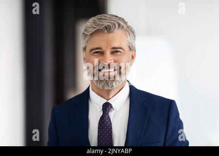 Portrait Of Handsome Smiling Middle Aged Businessman Wearing Suit Looking At Camera Stock Photo