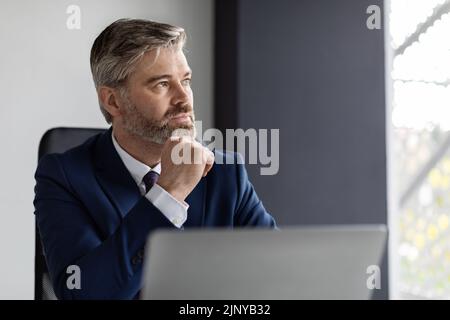 Business Planning. Portrait Of Thoughtful Mature Businessman At Workplace In Office Stock Photo