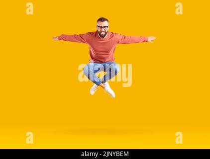Excited energetic young Caucasian man jumping celebrating success posing in orange studio Stock Photo