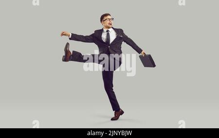 Businessman with crazy facial expression walking strangely, isolated on gray background. Stock Photo