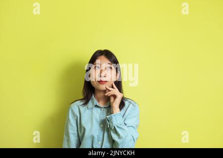 Thoughtful Asian Female Thinking Posing Looking Aside Over Yellow Background Stock Photo