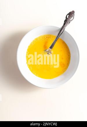 A beaten egg in bowl. Top view. White background. Close up. Stock Photo