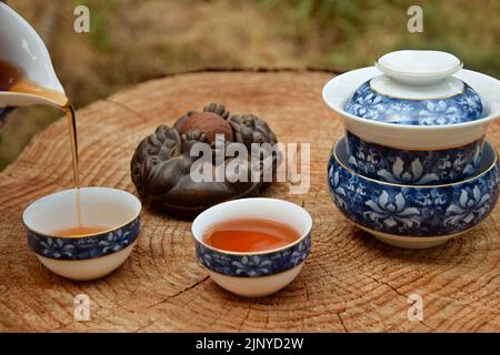 Preparing Chinese black tea in the tea set on the wooden table. Drink tea in the nature. Stock Photo