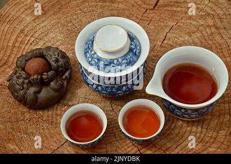 Preparing Chinese black tea in the tea set on the wooden table. Drinking tea in the nature. Stock Photo