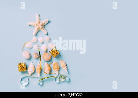 Christmas tree from sea shells, starfish alternative decoration blue background, new year by sea Stock Photo