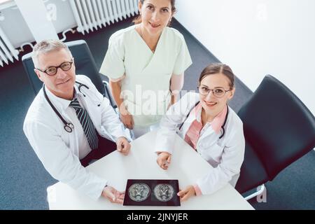 Team of doctors and nurses in meeting using a tablet computer Stock Photo