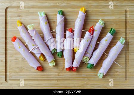 Cheerful sausage rolls with raw vegetables. Light snack with cucumber, sweet pepper, celery, cabbage leaves, hot chili pepper Stock Photo