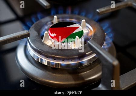 Gas import and export concept. A burning gas burner of a home stove, in the middle of which a flag is depicted - Jordan Stock Photo