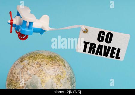 Travel and business concept. On a blue background, a globe and an airplane with a sign - Go travel. Globe out of focus. Stock Photo