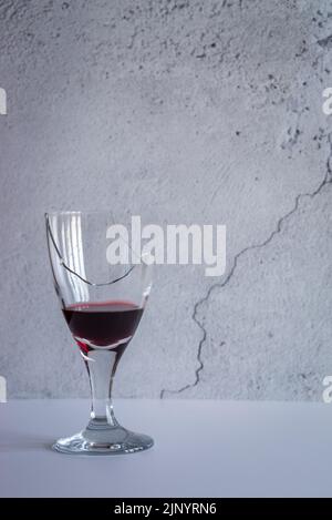 Broken, shattered wine glass quarter filled with red wine - studio shot Stock Photo