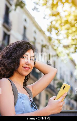 vertical portrait of an attractive young indian woman looking at camera. She is leaning on a fence and looking away Stock Photo