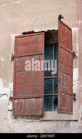 Exterior of old crumbling building has a single window with a wood frame that may has glass and iron shutters. This is a closeup view in Croatia. Stock Photo