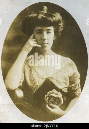 Vintage studio photograph of young woman taken in the early 20th century She is making a hand gesture that looks like Call Me This closeup portrait is circa 1900