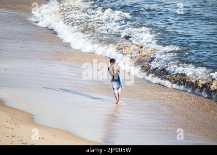 Salvador, Bahia, Brazil - November 01, 2021: Surfer entering the water of Rio Vermelho beach in Salvador, Bahia. Stock Photo