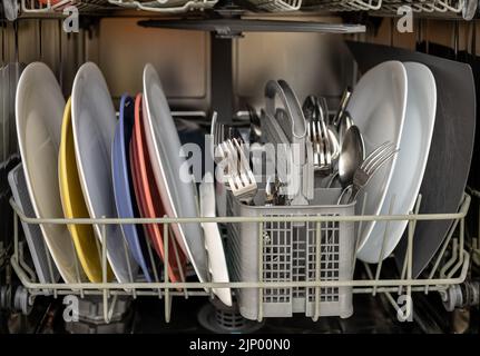 open dishwasher with clean dishes, utensils and pots Stock Photo