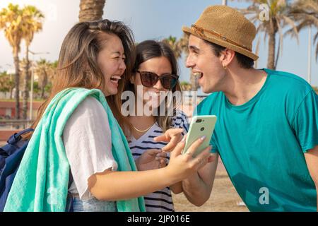 Multicultural group of trendy young friends laughing looking the smartphone. Stock Photo