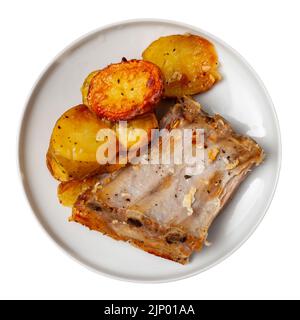 Pork ribs with boiled potatoes and spices on ceramic plate Stock Photo