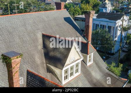 NEW ORLEANS, LA, USA - JANUARY 13, 2022: Aerial view of rooftop of historic Garden District home showing sloped roof, vintage chimneys and window Stock Photo