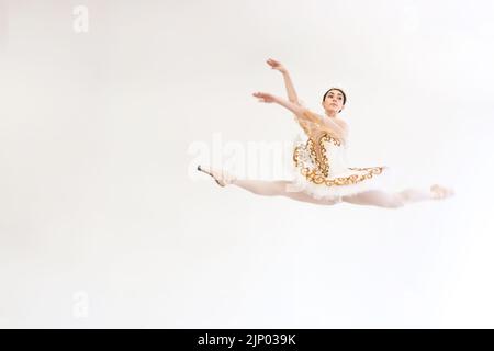 A young charming ballerina does ballet exercises in a jump against a white background Stock Photo