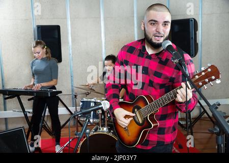 Bearded guy soloist playing guitar in studio Stock Photo