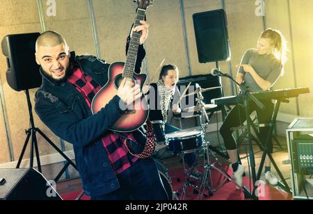 Guy guitar player and singer practicing with band members in re Stock Photo