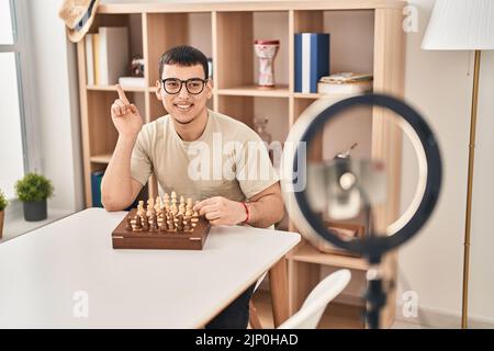 Young arab man doing chess tutorial smiling happy pointing with hand and finger to the side Stock Photo