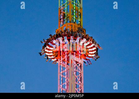 Herne, NRW, Germany. 14th Aug, 2022. People scream and laugh on the illuminated, 85m high 'Hangover - The Tower' thrill ride. Cranger Kirmes, Germany's 3rd largest funfair with a tradition dating back to the middle ages, has returned to pre-pandemic visitor numbers with more than 3.9m attending in hot, sunny weather, enjoying the rides, rollercoasters, beer halls, food and drink. The funfair concluded tonight with fireworks over the nearby Rhine-Herne Canal. Credit: Imageplotter/Alamy Live News Stock Photo