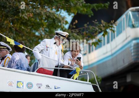 Members of the Seafair Commodores take photos as the Seattle Center Monorail passes by during preparations for the Seafair Torchlight Parade in Seattl