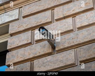 Video surveillance in a public area. CCTV camera mounted on an exterior wall of a government building. A black video camera is pointing somewhere. Stock Photo