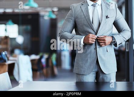 Confidence forms part of how you attire yourself as well. Closeup shot of an unrecognizable businessman fastening the button on his suit in an office. Stock Photo