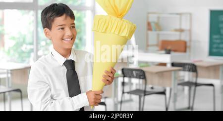 Happy little boy with school cone in classroom Stock Photo