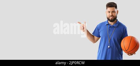 Portrait of male PE teacher pointing at something on light background with space for text Stock Photo