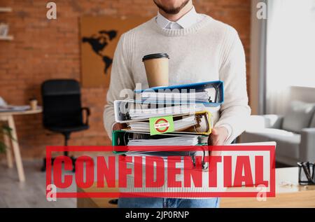 Young man holding folders with top secret documents in office Stock Photo