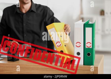 Young man working with top secret documents in office Stock Photo