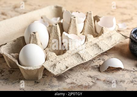 Cardboard holder with broken egg shells on grunge background Stock Photo