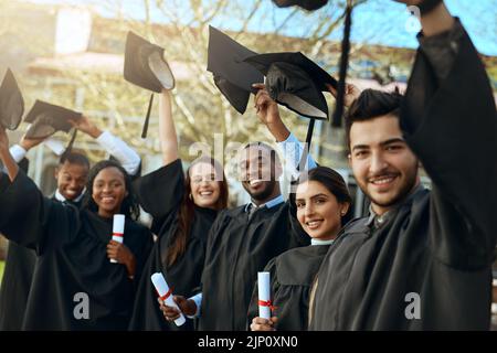 Nothings going to stand in our way now. Portrait of a group of happy young students taking their hats off on graduation day. Stock Photo