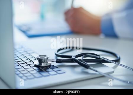 Technology - the greatest tool for medical advancement. Closeup shot of a stethoscope resting on a laptop with an unrecognizable doctor working in the Stock Photo