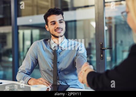Nothing strengthens a business deal like trust. a young businessman and businesswoman shaking hands during a meeting in a modern office. Stock Photo
