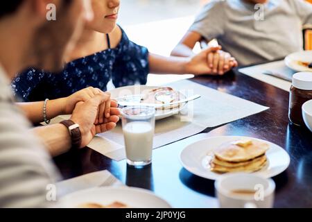 Its a blessing to be able to share this meal together. Closeup shot of a family praying before enjoying their meal together at home. Stock Photo