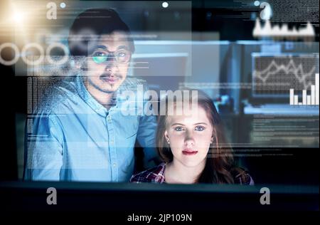 Working together to get the job done nicely. Portrait of two focussed young programmers working together on a computer in the office at work during Stock Photo
